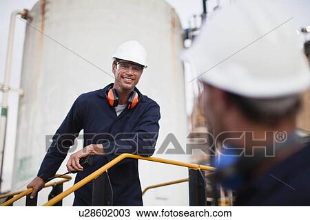 Stock Image - Workers talking at chemical plant. Fotosearch
