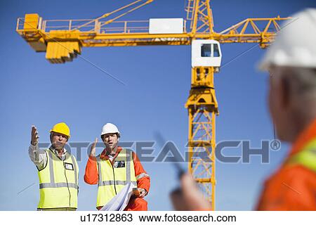 Workers talking at construction site View Large Photo Image Stock Image - Workers talking at construction site. Fotosearch