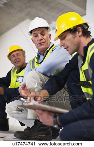 Workers talking at construction site View Large Photo Image Stock Image - Workers talking at construction site. Fotosearch