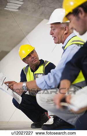 Workers talking at construction site View Large Photo Image Stock Photo - Workers talking at construction site. Fotosearch