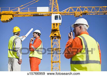 Stock Photo - Workers talking at construction site. Fotosearch