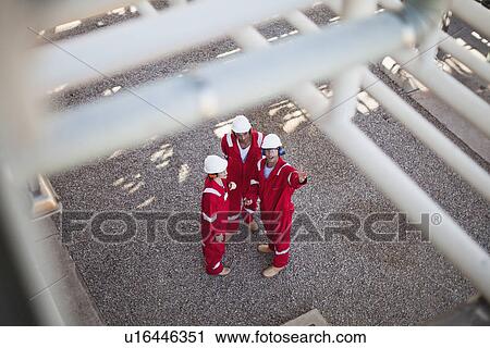 Stock Image - Workers talking at oil refinery. Fotosearch