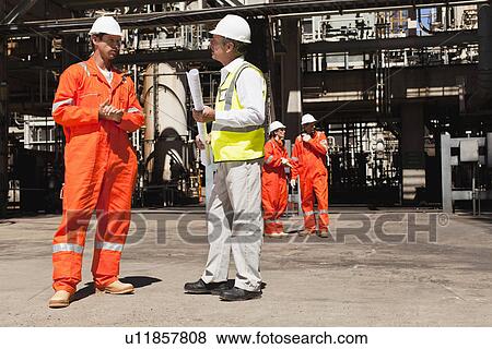Workers talking at oil refinery View Large Photo Image Stock Photo - Workers talking at oil refinery. Fotosearch