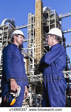 Stock Photo - Workers talking at oil refinery. Fotosearch