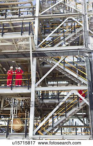 Workers talking at oil refinery View Large Photo Image Stock Photo - Workers talking at oil refinery. Fotosearch