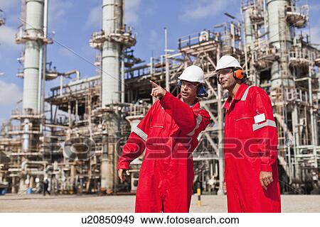 Stock Photo - Workers talking at oil refinery. Fotosearch