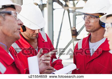 Workers talking at oil refinery View Large Photo Image Stock Photo - Workers talking at oil refinery. Fotosearch