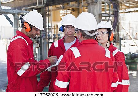 Workers talking at oil refinery View Large Photo Image Stock Photograph - Workers talking at oil refinery. Fotosearch