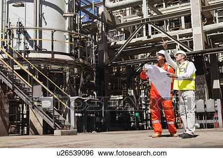 Stock Photograph - Workers talking at oil refinery. Fotosearch