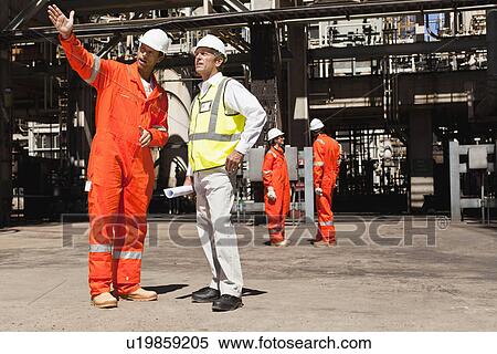 Workers talking at oil refinery View Large Photo Image Stock Photography - Workers talking at oil refinery. Fotosearch