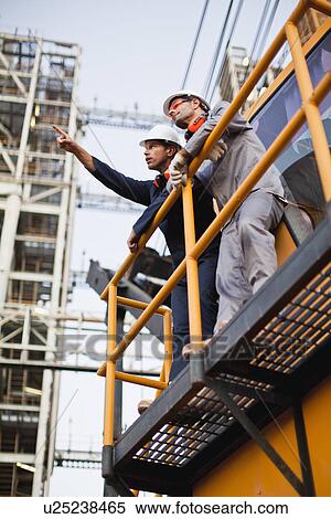 Stock Photography - Workers talking at oil refinery. Fotosearch
