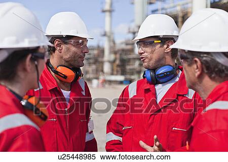 Stock Photography - Workers talking at oil refinery. Fotosearch