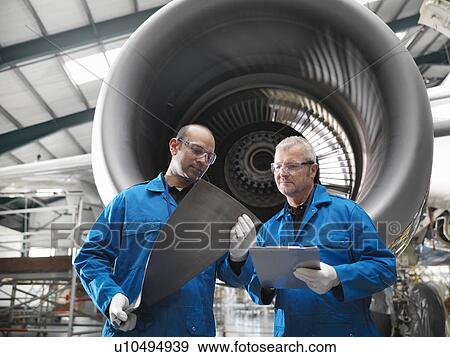 Stock Photo - Workers talking in airplane hangar. Fotosearch