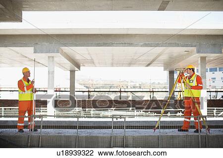 Stock Image - Workers using equipment on site. Fotosearch