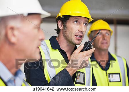 Workers using walkie talkie on site View Large Photo Image Stock Image - Workers using walkie talkie on site. Fotosearch