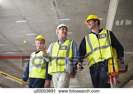 Workers walking at construction site View Large Photo Image Stock Image - Workers walking at construction site. Fotosearch