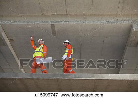 Stock Photo - Workers walking at construction site. Fotosearch