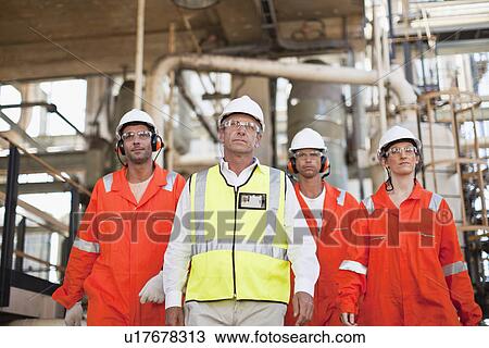 Stock Image - Workers walking at oil refinery. Fotosearch