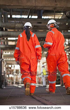 Stock Photograph - Workers walking at oil refinery. Fotosearch