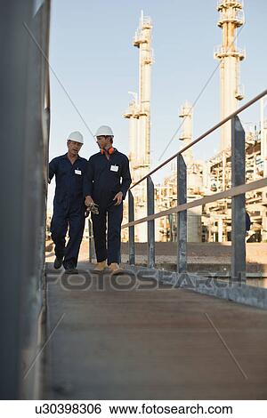 Stock Photograph - Workers walking at oil refinery. Fotosearch