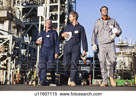 Stock Photography - Workers walking at oil refinery. Fotosearch