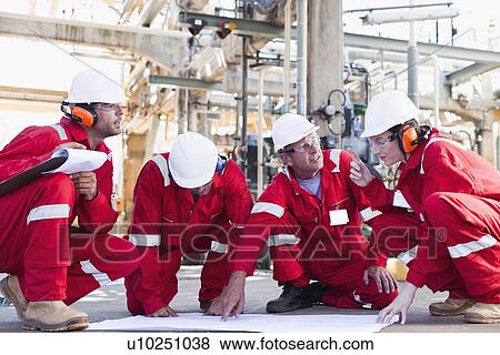 Stock Photo - Workers with blueprints at oil refinery. Fotosearch