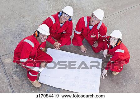 Stock Photo - Workers with blueprints at oil refinery. Fotosearch