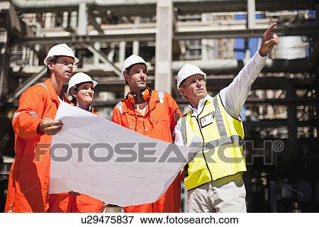 Stock Photo - Workers with blueprints at oil refinery. Fotosearch