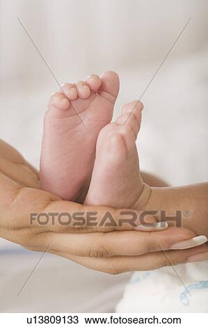 Stock Image - Baby feet on a woman's hand. Fotosearch