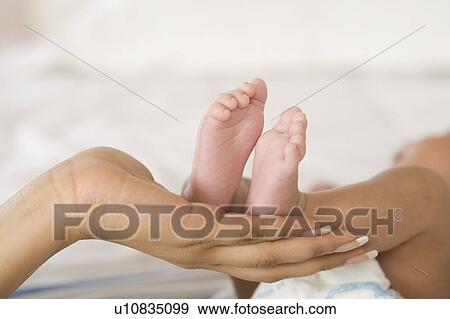 Stock Photo - Baby feet on a woman's hand. Fotosearch