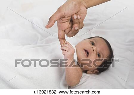 Stock Image - Baby holding finger of mother. Fotosearch