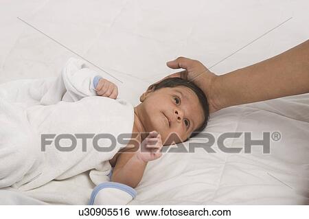 Baby lying on the bed View Large Photo Image Stock Photograph - Baby lying on the bed. Fotosearch