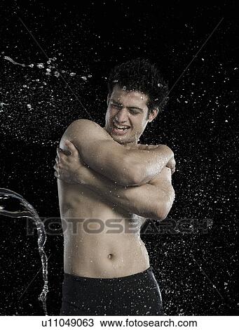 Stock Image - Bare chested man splashed with water. Fotosearch