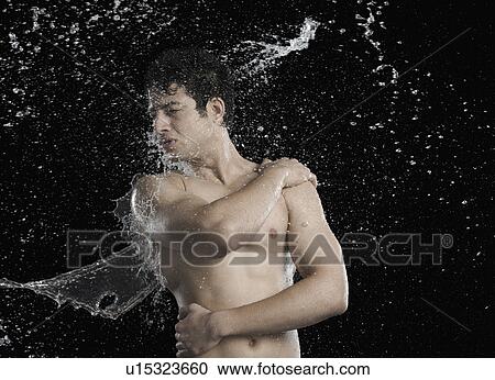 Stock Image - Bare chested man splashed with water. Fotosearch