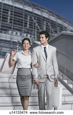 Business couple moving down staircase of a shopping mall View Large Photo Image Picture - Business couple moving down staircase of a shopping mall. Fotosearch