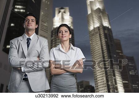 Stock Image - Business couple standing in a city. Fotosearch