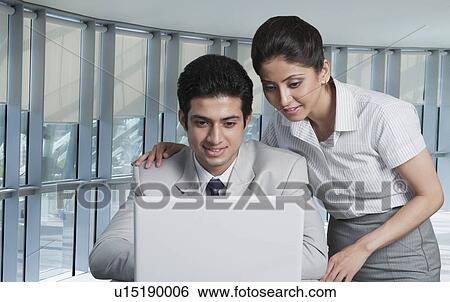 Business couple working on a laptop View Large Photo Image Stock Photograph - Business couple working on a laptop. Fotosearch