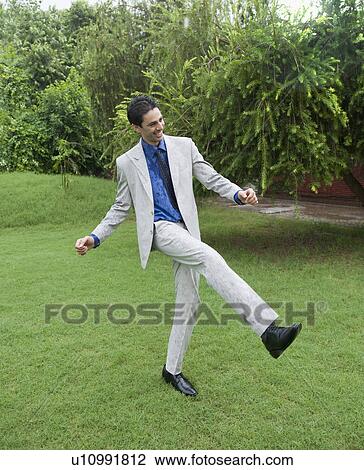 Stock Image - Businessman dancing in the rain. Fotosearch