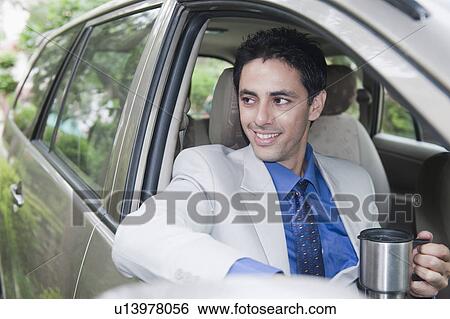 Businessman drinking coffee while driving a car View Large Photo Image Stock Photograph - Businessman drinking coffee while driving a car. Fotosearch