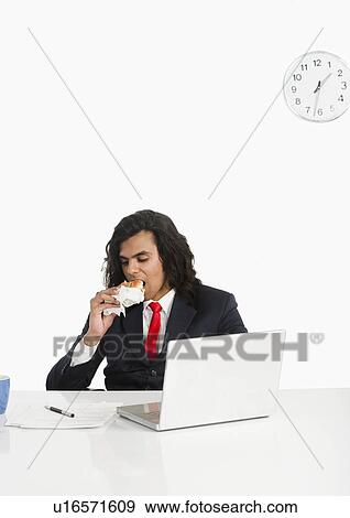 Businessman eating a burger at the desk View Large Photo Image Stock Photo - Businessman eating a burger at the desk. Fotosearch