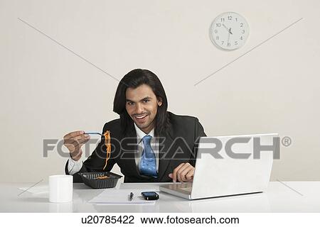Businessman eating noodles at the desk View Large Photo Image Stock Image - Businessman eating noodles at the desk. Fotosearch