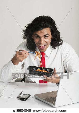 Businessman eating noodles at the desk View Large Photo Image Stock Photography - Businessman eating noodles at the desk. Fotosearch