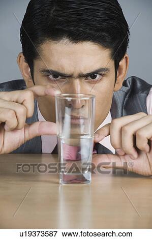 Businessman examining glass of water View Large Photo Image Stock Photo - Businessman examining glass of water. Fotosearch