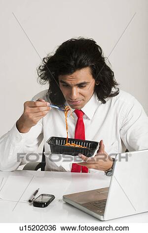 Stock Photograph - Businessman frowning at a bowl of noodles. Fotosearch