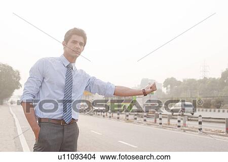 Businessman hitchhiking, Gurgaon, Haryana, India View Large Photo Image Picture - Businessman hitchhiking, Gurgaon, Haryana, India. Fotosearch