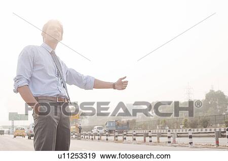 Businessman hitchhiking, Gurgaon, Haryana, India View Large Photo Image Stock Photo - Businessman hitchhiking, Gurgaon, Haryana, India. Fotosearch