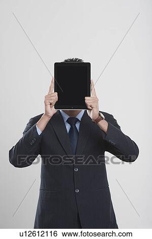 Businessman holding a digital tablet in front of his face View Large Photo Image Stock Photograph - Businessman holding a digital tablet in front of his face. Fotosearch