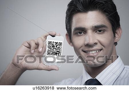 Businessman holding a mobile phone with 2D barcode on its screen View Large Photo Image Stock Photo - Businessman holding a mobile phone with 2D barcode on its screen. Fotosearch