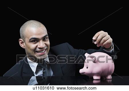 Businessman inserting a coin into a piggy bank View Large Photo Image Stock Image - Businessman inserting a coin into a piggy bank. Fotosearch