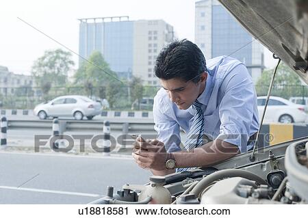 Businessman leaning on a broken down car and using mobile phone, Gurgaon, Haryana, India View Large Photo Image Stock Image - Businessman leaning on a broken down car and using mobile phone, Gurgaon, Haryana, India. Fotosearch